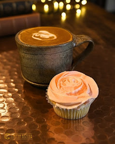 A latte and frosted cupcake on a copper table